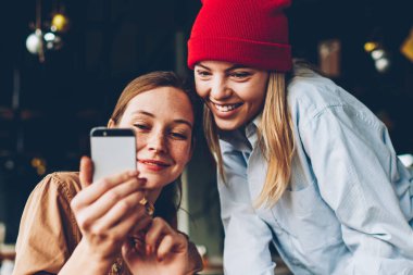 Neşeli iki hipsters smartphone aygıt komik video online izleme bağlı 4 g için Internet. Pozitif gençler sosyal ağlar üzerinde cep telefonu birlikte dinlenme kafe iç kontrol