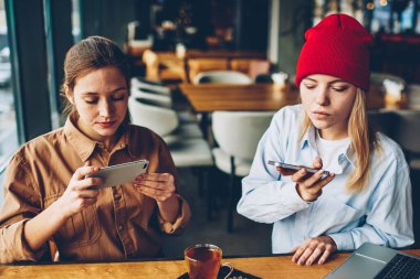 Sosyal ağlar birlikte Cafe iç dinlenme yayında modern smartphone cep telefonu ile fotoğraf lezzetli çay yaparken görmezden canlı iletişim bağımlısı gençler içinde şık casual giyinen giymek