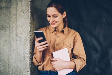 Smartphone aygıt profili güncelleştirmek için 4 g bağlıyken neşeli hipster blogger gülüyor Internet. Pozitif öğrenci ders kitabı elinde telefon sosyal ağlarda komik Haberler okuma ile