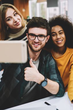 Ön kameraya poz ve komik selfies smartphone üzerinde beyin fırtınası sırasında yapmak mutlu kadın ve erkek öğrenciler. Çekim telefonla sonra başarılı işbirliği çeşitlilik tasarımcılar ekibi