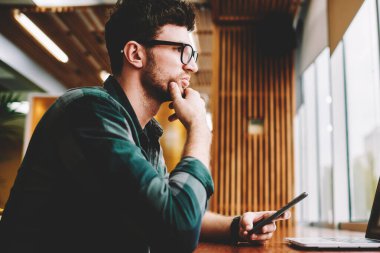 Genç profesyonel bu geliştirici başlangıç için yaratıcı fikirler hakkında durulması vizyon düzeltme için gözlük takıyor. Dizüstü bilgisayarda uygulama yüklerken program planlama sakallı hippi adam