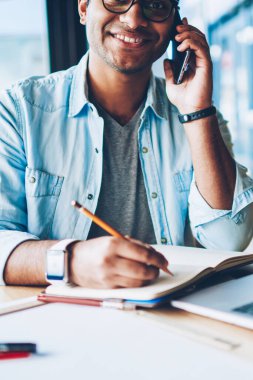 Mobil istemci ile 4 g için bağlı telefonda konuşmayı gülümseyen profesyonel Freelancer yarım uzunluk portre. Arkadaşlarınızla konuşurken ve Not defteri bilgileri kaydetmek mutlu erkek kişi