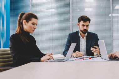 Dalgın iki profesyonel finans şirketi patronla tablo toplantıda çalışma brifing sırasında dizüstü bilgisayarlarda bilgi aramak. Gurur CEO'su posta smartphone meslektaşları ile işbirliği üzerinde kontrol