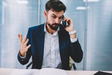 Öfkeli işadamı el eller ve smartphone için işlecini çağırmak çözme bankacılık sorunu. Telefon görüşmesi sırasında cep üzerinde çalışma sırasında office savunarak kızgın icra müdürü