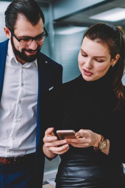 Bir ara iş toplantı sırasında mobil telefon elinde gülümseyen çalışanlar odaklanarak Office masada oturan ve akıllı telefon, video izlerken iki genç çekici sahip insanlar mutlu iş arkadaşları