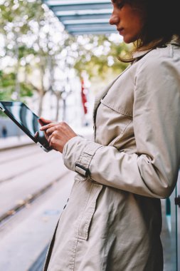 Posta kontrol ve bildirim istimal özgür 4 g dokunmatik yüzey üzerinde okuma trendy ceket genç kadın yan görünüm kırpılmış Internet. Dalgın kadın blogger profil sayfası tramvay durağı tablet ayakta güncelleştiriliyor