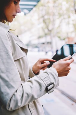 Modern Dokunmatik ped cihaz ücretsiz 4 g internet bağlantısı üzerinden indirmek için uygulama seçimi rahat giyinmiş hippi kız yan görünüm. Genç kadın tramvay durağı kentsel ortamda ayakta e-kitap okuma