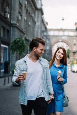 Neşeli, genç, çekici bir kadın ve yakışıklı bir erkek el ele tutuşup dondurma yerken ve şehirde romantik bir buluşmada yürürken eğleniyorlar.