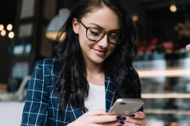 Akıllı telefonlara ve müşterilere mesajlar gönderirken planlamacıyla birlikte kahve barında çalışan meşgul bir kadın girişimci.