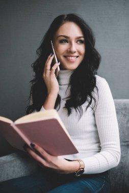 Genç bayan girişimci rahat koltukta rahat bir şekilde oturmuş, akıllı telefonla konuşurken not defterindeki bilgileri kontrol ediyor ve gözlerini kaçırıyordu.