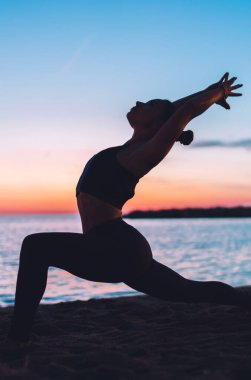 Aktif giyinen esnek kadın yoga pozu veriyor. Pranayama solunumu ve dinlenme için zaman ayırıyor. Asya 'da oturan zinde kız deniz kıyısındaki uyuma ulaşan sakinlik ve sağlık duygusunu hissediyor.