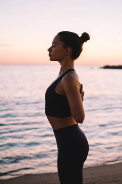 Aktif giyinen, yoga antrenmanından keyif alan, Asya 'da dinlenen güçlü atletik kadın, meditasyon sırasında canlılık ve refahı hissetmek için açık havada antrenman yapıyor.