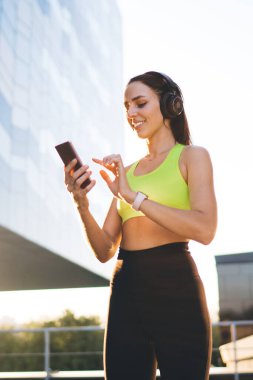 Aktif giyimli Kafkasyalı sporcu kız, takipçileriyle sabah egzersizi hakkında cep telefonunda mesajlar gönderiyor, 20 'li yaşlarda gülümseyen kadın koşucu, akıllı telefon aracılığıyla blogdaki içeriği paylaşıyor.