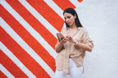 Kafkasya milenyumu akıllı telefondan internet sitesinde taşınabilirlik rezervasyonu yapmak için 4G 'ye bağlanıyor, güzel kız tanıtım alanında duran içerik metinlerini okumak için cep telefonu aygıtı kullanıyor