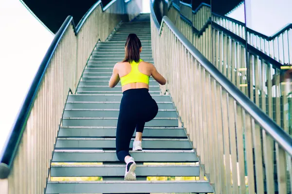 Beyaz tenli bayan sporcunun, zayıf figürlü spor yaparken merdivenlerde çömelme egzersizleri yaparken, spor kıyafetleri içinde kadın spor kıyafetleri giyerken, spor hedeflerine ulaşırken, bacak kasları ve açık havada canlılık eğitimi alırken.