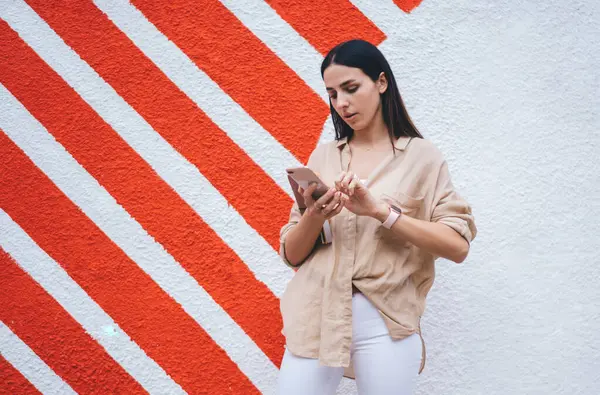 Kafkasya milenyumu akıllı telefondan internet sitesinde taşınabilirlik rezervasyonu yapmak için 4G 'ye bağlanıyor, güzel kız tanıtım alanında duran içerik metinlerini okumak için cep telefonu aygıtı kullanıyor