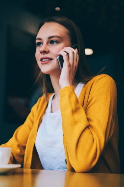 Cep telefonuyla konuşan çekici bir hippi kız kafeteryada oturuyor, güzel bir kadın akıllı telefondan arıyor yüksek hızlı bağlantıyı kullanarak kahve molası veriyor.