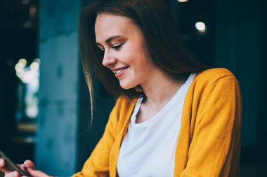 Mutlu hippi kız akıllı telefon cihazıyla internette geziniyor kafede oturuyor, başarılı kadın sosyal ağlarda arkadaşlarıyla sohbet ederken cep telefonunda ücretsiz kablosuz bağlantı kullanıyor.