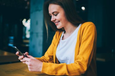 Mutlu hippi kız akıllı telefon cihazıyla internette geziniyor kafede oturuyor, başarılı kadın sosyal ağlarda arkadaşlarıyla sohbet ederken cep telefonunda ücretsiz kablosuz bağlantı kullanıyor.