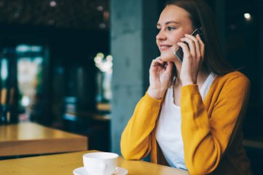Kafeteryada kafein içeceğiyle dinlenen ve akıllı telefon aracılığıyla arkadaşlarıyla konuşan, dijital cep telefonuyla konuşan, komik hippi kız kafenin içinde yüksek hızlı mobil bağlantı kullanıyor.