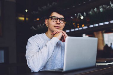 Modern bilgisayarda çalışan ve üretkenlik çalışması için ücretsiz 4G internet bağlantısı kullanan gözlüklerde başarılı bir programcı. Optik gözlüklerde deneyimli bir metin yazarı dizüstü bilgisayarın başında oturuyor.