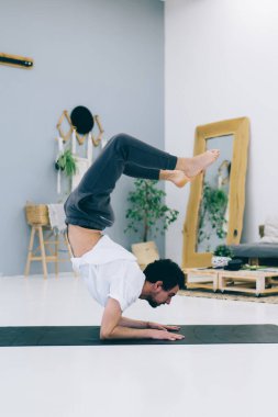 Akrep Çene 'yi çalıştıran esnek adamın yan görüntüsü böylece kalçaları ve bacakları kapalı alanda güçlendirir.