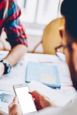 İnternet içeriğiniz için boş ekran alanı olan modern akıllı telefona mobil uygulama yükleyen genç bir adamın arka görüntüsü. Hipster adam telefon tutan ve internet üzerinden sohbet eden biri.