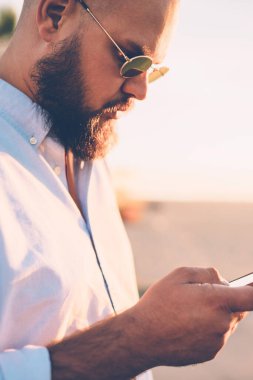 Mobil telefon Web sitesi üzerinden uygulama, rezervasyon yapma sakallı hippi adam yakın çekim gencin sosyal ağlarda şehir sokak arkadaş sohbet akıllı telefon kısa mesajla gönderme