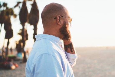 Genç hipster adam görünümlü dış görev seslenmek yolu ile smartphone ile arkadaş açık havada, yakışıklı erkek gezici telefon konuşmayı konuşurken bağlantı ve cep telefonu ile memnun tarifeler