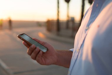 Sakallı erkek holding cep telefonu haber bilgi göz web sayfası ayakta Caddesi üzerinde okuma, Resim kırpılmış, hipster adam görüş fotoğraf içinde sosyal ağlar bloglama online yolu ile smartphone