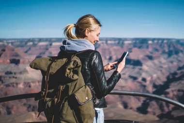 Dağlarda, pozitif kadın Gezgin vahşi doğa keşfetmek akıllı ileti gönderme turistik güzergah üzerinde hiking iyi mobil bağlantı kontrol sırt çantası ile genç hippi kız avare gülümseyen