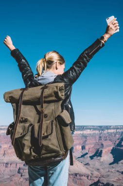 Genç kadın Gezgin Arizona Milli Park, Grand Canyon Vadisi üzerinde kayalık uçurum ayakta eller yükselterek hippi kız duygu özgürlük keşfetmek dağın tepesine ulaşan başarı kutluyor