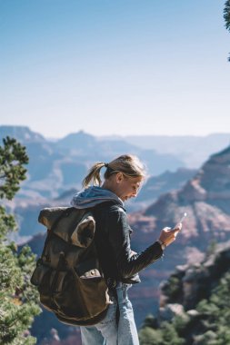 Vahşi ortamda, hippi kız tur smartphone uygulama kullanarak hiking sırasında gezinme iletişim için telefon bağlantısı dolaşım olması ile sırt çantası ile gülümseyen kadın turist memnun