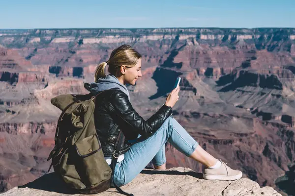 Milli Park, dağ tepe üzerinde yürüyüş sırasında hücresel dinlenme üstünde posta kontrol kadın turist Yolculuk tutkusu kayalık uçurum üzerinden ileti göndermek için mobil bağlantı kullanarak sırt çantası ile gülümseyen kız