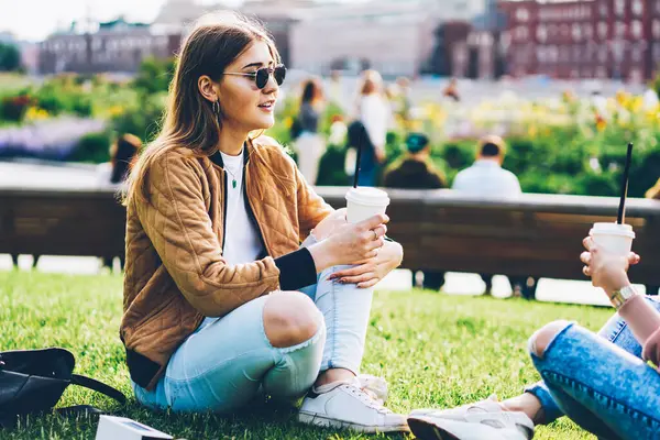 Yeşil çimenlerin üzerinde oturan ve birbirleriyle dost toplantı sırasında iletişim kurma elinde lezzetli kahve iki hippi kız. Açık havada harcama söz şık güneş gözlüğü öğrencilerin boş zaman parkta