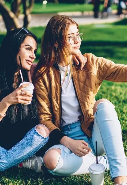 Parkta birlikte vakit smartphone kamera selfie yapmak için poz neşeli arkadaşlarım. Mutlu hippi kız trendy kıyafeti için hareket eden aygıt yolu ile sosyal ağlar uploading fotoğraf çekmek