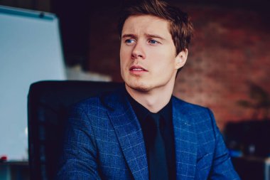 Takım elbiseli, kafası karışık bir iş adamı bilgisayarında bilgisayarlı bir cihazla yeni başlatılan proje üzerinde kafa yoruyor. Düşünceli erkek iş arkadaşı, modern netbook aracılığıyla iş arkadaşlarıyla iletişim kuruyor.