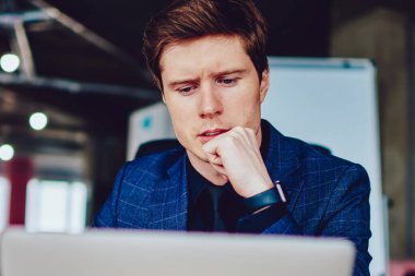 Şaşkın erkek çalışan önemli web sitelerini izlerken ders kitabında ana bilgileri yazarken, düşünceli beyaz girişimci sosyal ağlarda haberleri okurken modern netbook 'ta 4G bağlantısı kullanıyor.