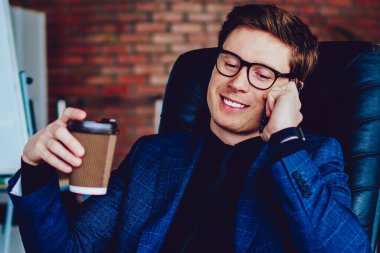 Başarılı bir iş adamı arkadaşlarıyla uygulama üzerinden olumlu bir konuşma yaparken içerideki kafein içeceklerinin keyfini çıkarıyor, akıllı telefon cihazıyla ofisteki Wi-Fi 'ye bağlanan mutlu işveren arıyor.