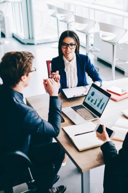 İki bayan meslektaşı, erkek finans müdürü ile önemli bir toplantı yapıyor. İçerideki ticaretin detaylarını tartışıyorlar. Bir grup ekonomist masaüstünde oturmuş istatistikler hakkında konuşuyorlar.