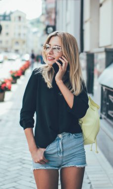 Kaygısız kadın gezmek için modern cep telefonu aygıtını kullanıyor. Tatil tatillerinde şehri keşfediyor. Güneş gözlüklü mutlu bir turist.