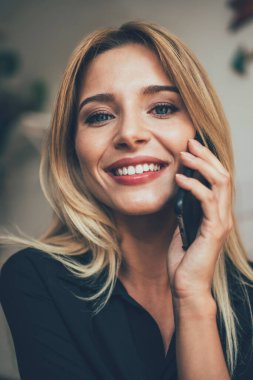 En iyi arkadaşıyla yaptığı olumlu cep telefonu konuşmasında kameraya gülümseyen neşeli kadın kullanıcının portresini kapat. Güzel beyaz kız cep telefonu uygulaması aracılığıyla telefon edip 4G iletişimi kuruyor.