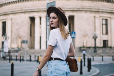 Beyaz tenli, modaya uygun giyinen ve şapka giyen bir kadın boş zamanlarında önemli yerlerde karşıdan karşıya geçerken dikkat çekici bir yeniyetme kız boş zamanlarını şehir merkezinde ilginç mekanlar ve varış noktalarında geçiriyor.