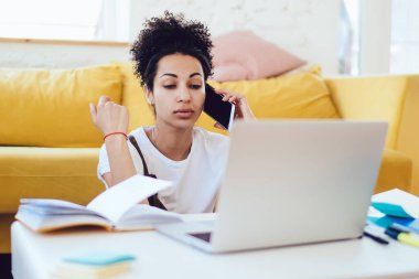 Genç, başarılı Afrikalı, serbest çalışan, günlük kıyafetli, akıllı telefon konuşması yapan, dizüstü bilgisayarlı, apartman dairesinde oturan,