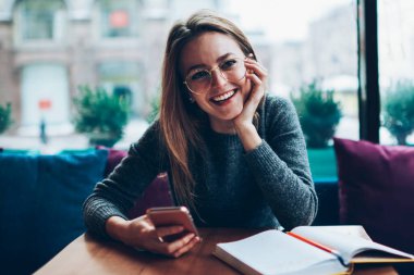 Gözlüklü neşeli hippi kızın portresi. Yüzünde sevimli bir gülümseme var. Hücresel, başarılı bir kız öğrenci.