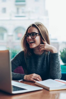 Genç mutlu bayan metin yazarı, yeni modern dizüstü bilgisayarla kafeteryada otururken yüzünde olumlu bir gülümsemeyle ev ödevini tamamlamaktan memnun kalmış tasasız bir öğrenci.
