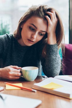 Kafeteryada sabah kahvesini yudumlarken kitap okuyan düşünceli genç bir kadın, 20 yaşında düşünceli, zeki hippi bir kız, edebiyat analizi yapıyor.