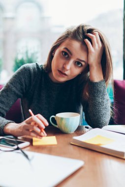 Üniversite kafeteryasında planlama için not defteriyle oturan genç ve ciddi bir kız öğrencinin portresi. Çekici hippi kız kameraya bakıyor ve ödev hazırlıyor. Çıkartmalarla notlar alıyor.