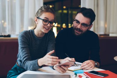 Elinde cep telefonu tutan gülümseyen hippi kız komik bir mesajdan dolayı kendini iyi hissediyor. Üniversite kafeteryasında internet bağlantısı olan akıllı telefon kullanan kadın erkek arkadaşıyla vakit geçiriyor.