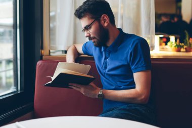 Yakışıklı sakin hippi, rahat kafeteryada dinlenirken ilginç bir kitap okuyor, şık gözlüklü genç erkek öğrenci romantik romanların keyfini çıkarıyor ve dinleniyor.